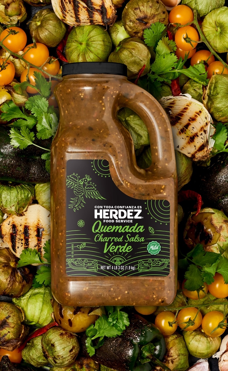 jug of Salsa Verde on a bed of charred veggies