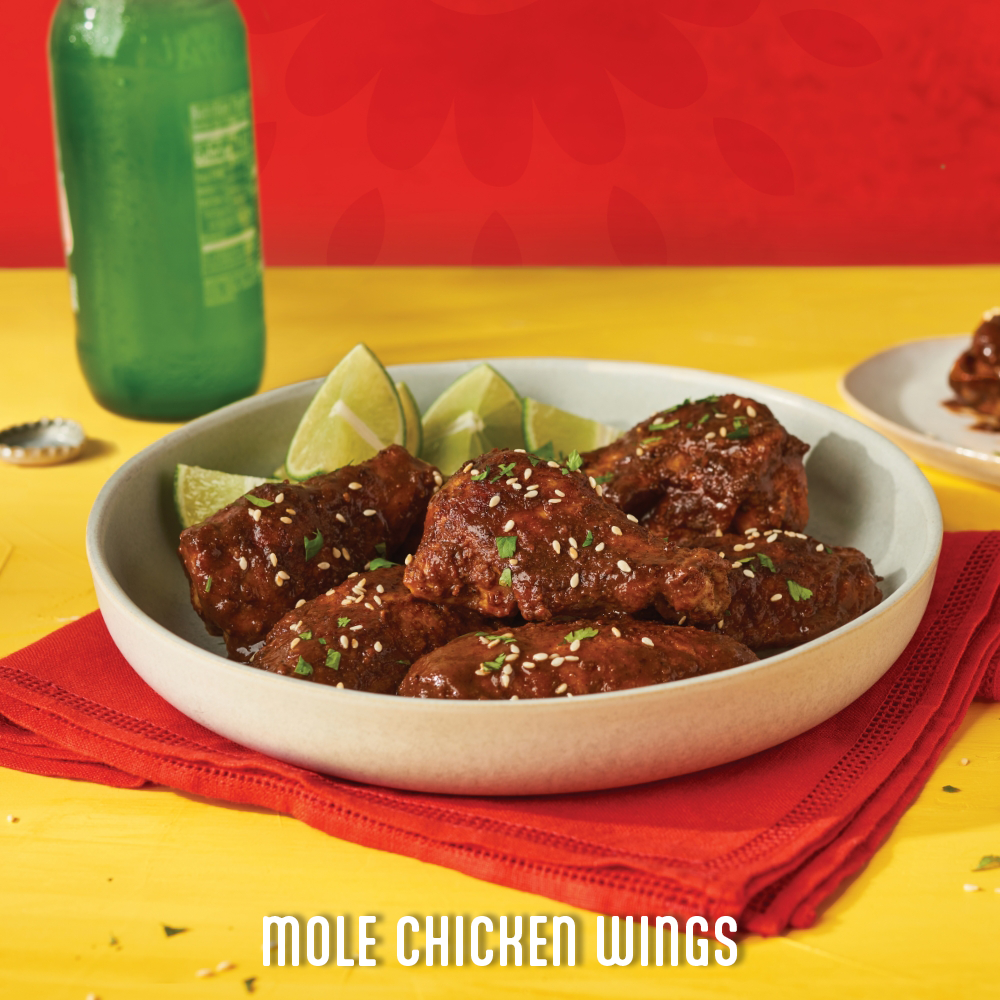 mole chicken wings in a bowl with lime wedges on the side